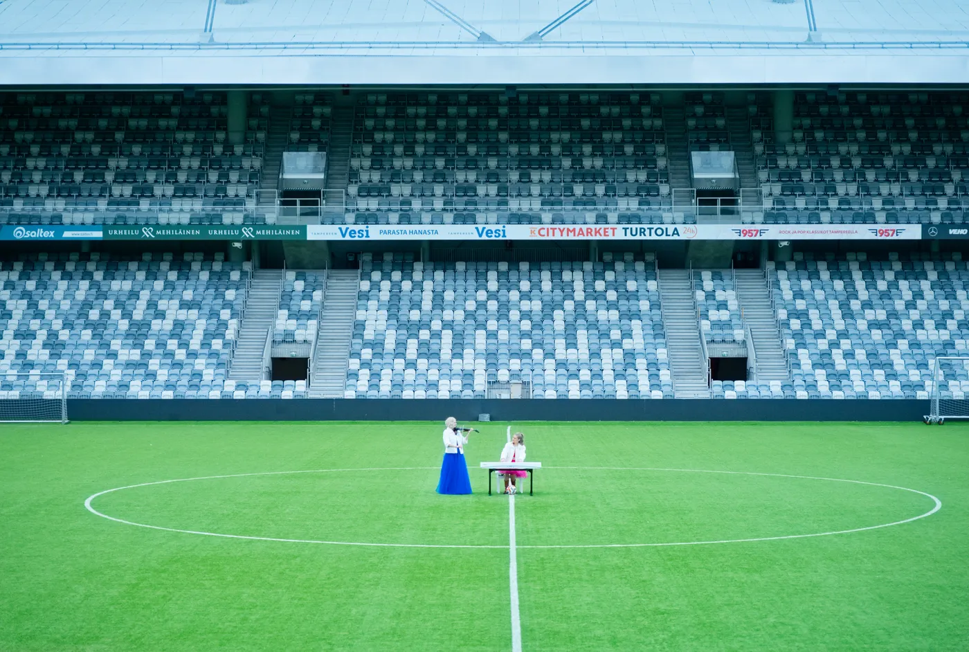 Viulisti ja pianisti tyhjän katsomon edessä Tammelan stadionilla