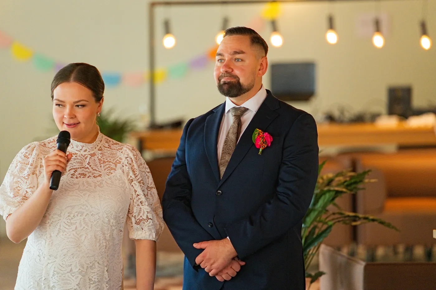Morsian puhuu mikrofoniin sulhanen vierellään juhlasalissa