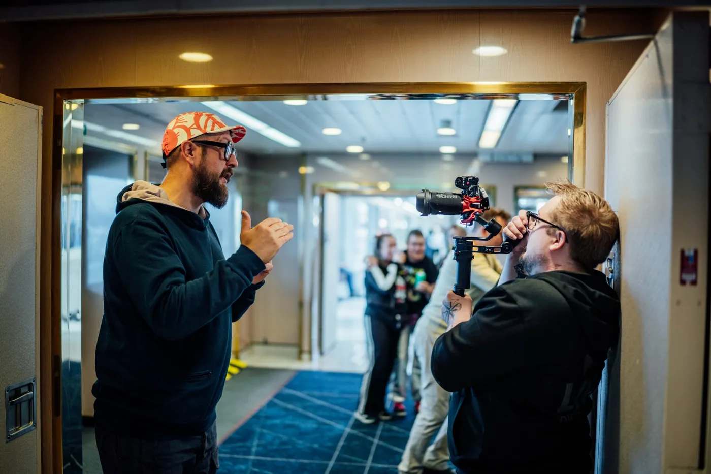 Kuvaaja kuvaamassa esiintyjää sisätiloissa videotuotannon aikana